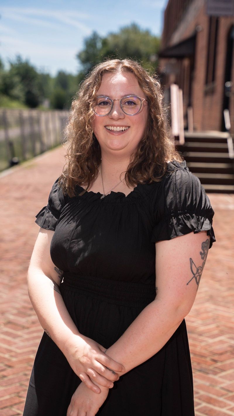 Smiling professional portrait of the Brooke Team recruit beside a brick building