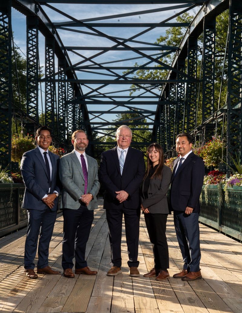 Dental team of the Center of Dental Excellence posed together outdoors, framed by a bridge