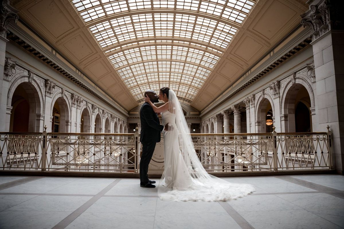 Christina and Tajay share a full-length kiss beneath the City Hall glass roof
