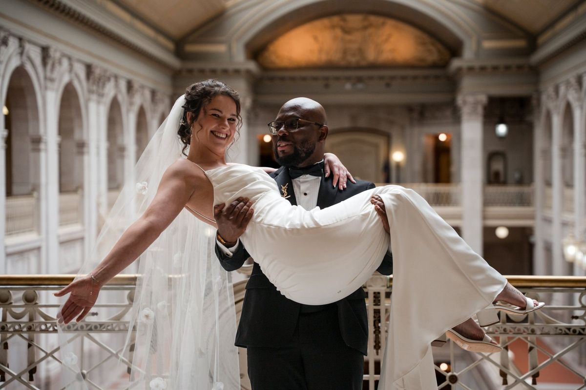 Tajay carries Christina as they laugh together beneath the Hartford City Hall skylight