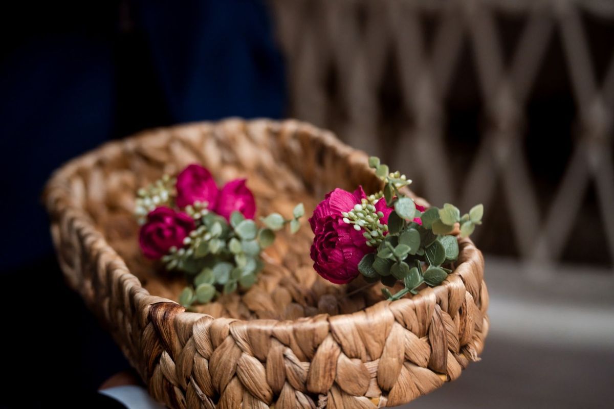 Pink flowers and greenery rest inside a woven basket