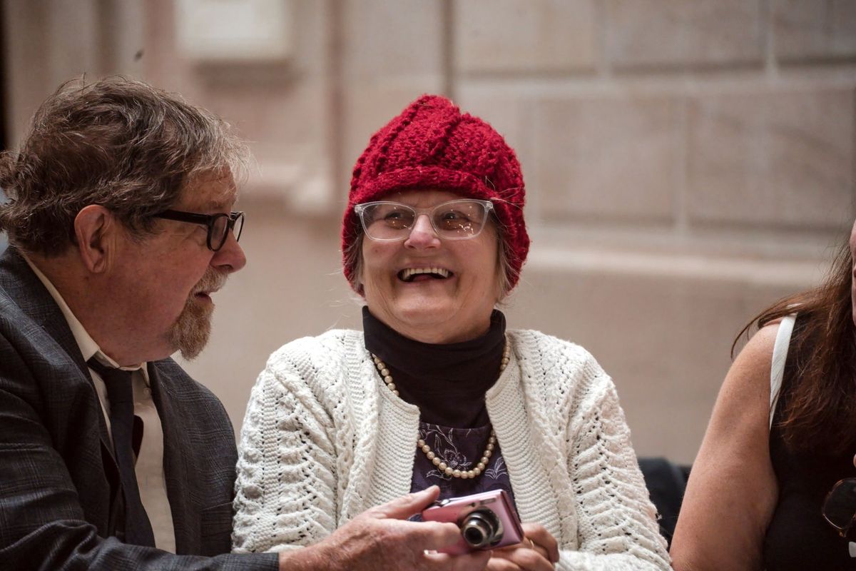 A guest in a red knit hat smiles during a conversation