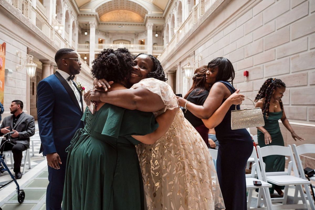 Guests greet one another with an embrace beside the ceremony chairs