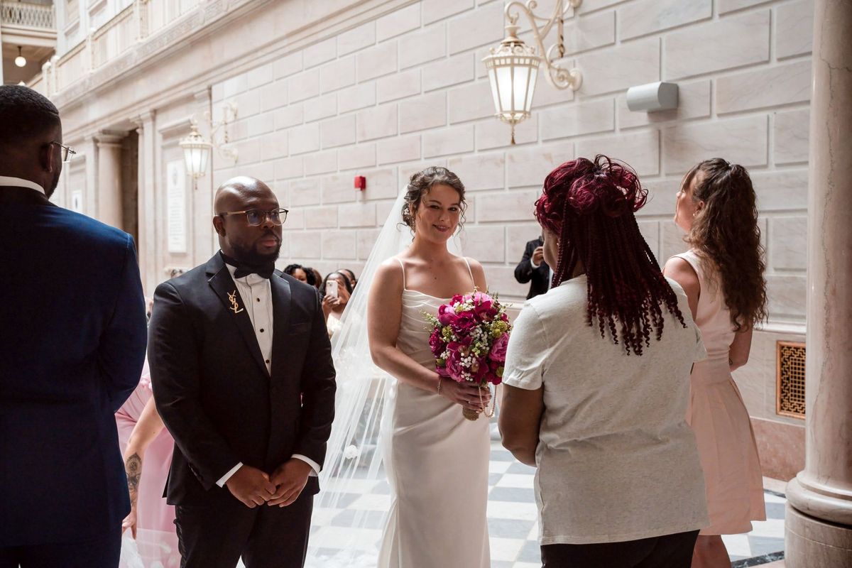 Christina and Tajay stand beside the officiant during their atrium ceremony