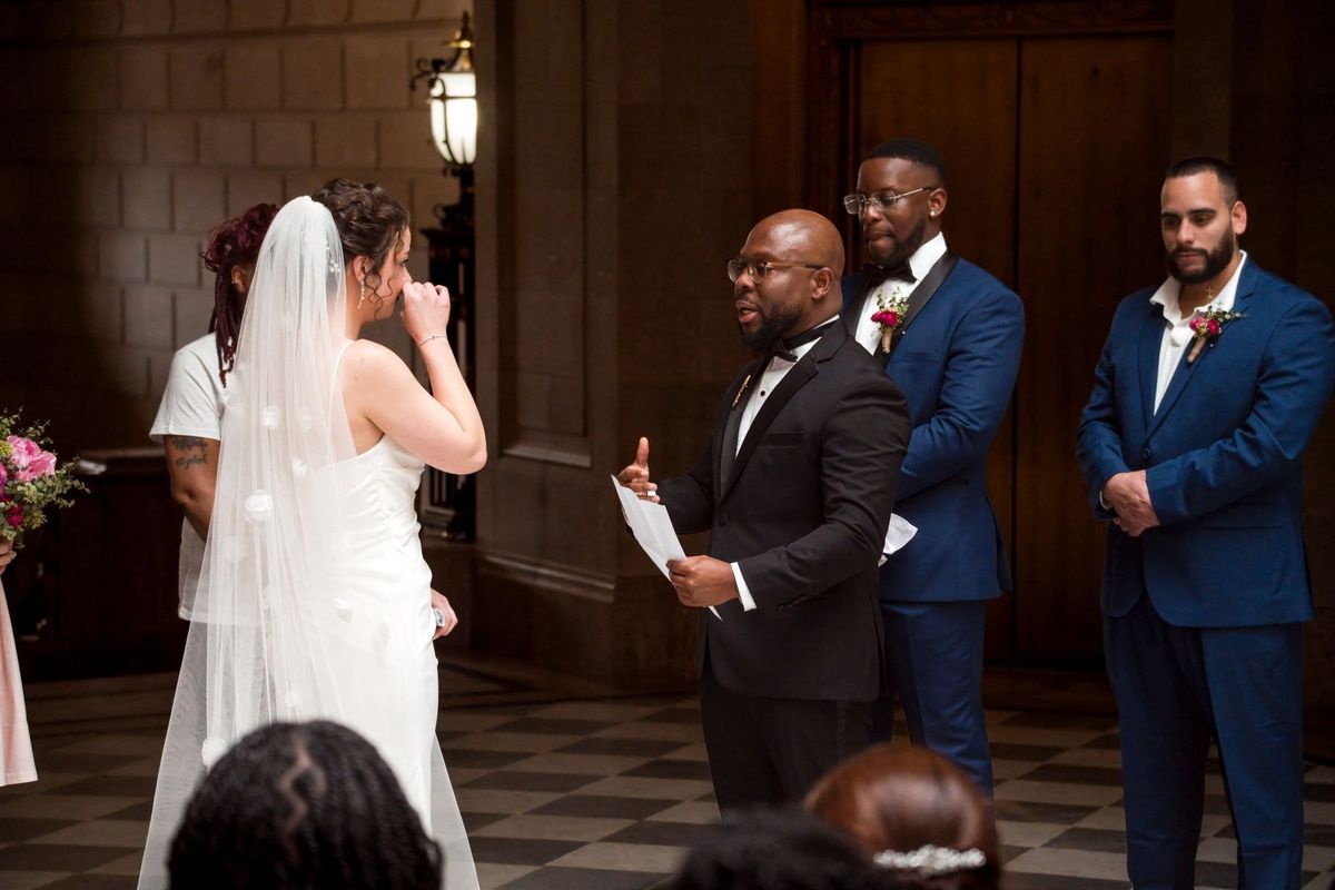 Tajay reads from a sheet of paper while facing Christina during the ceremony