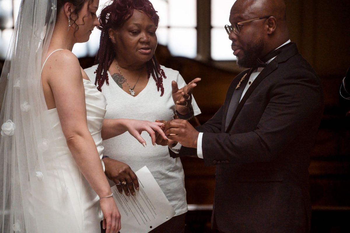 Tajay places a ring on Christina’s hand beside the officiant