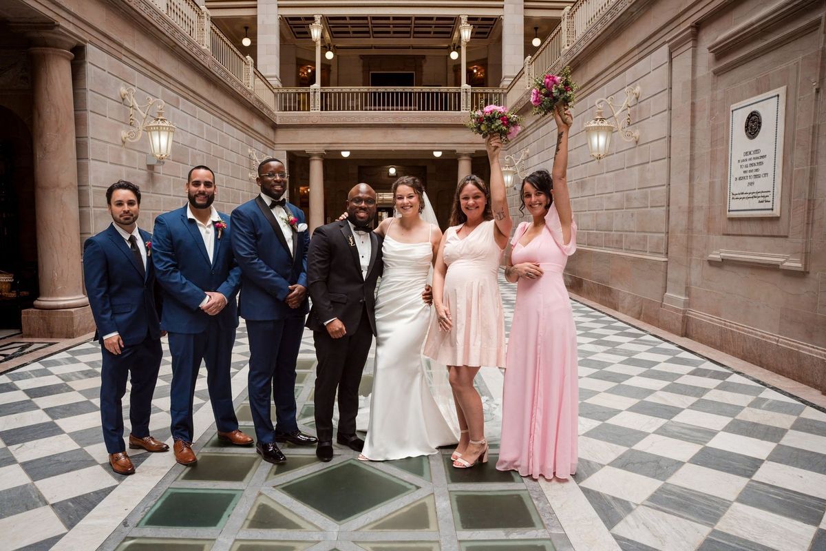 Christina and Tajay pose with their wedding party on the patterned atrium floor