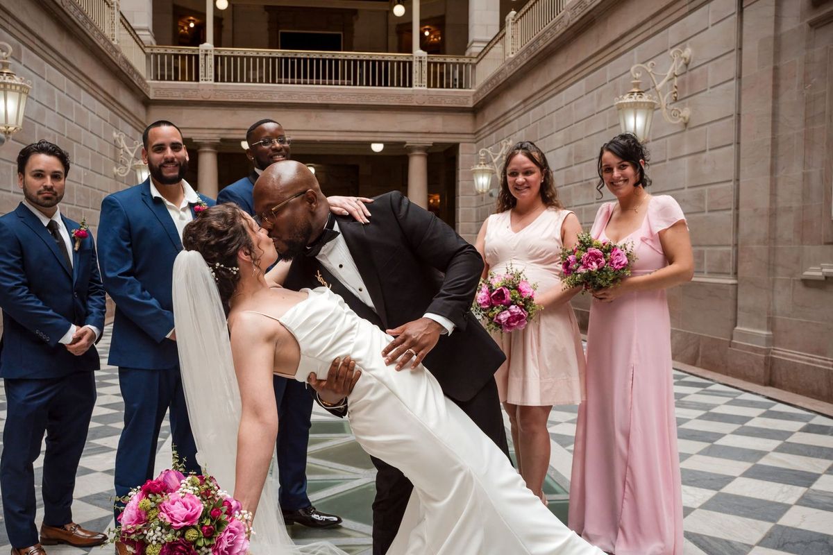 Tajay dips Christina into a kiss as their wedding party stands behind them
