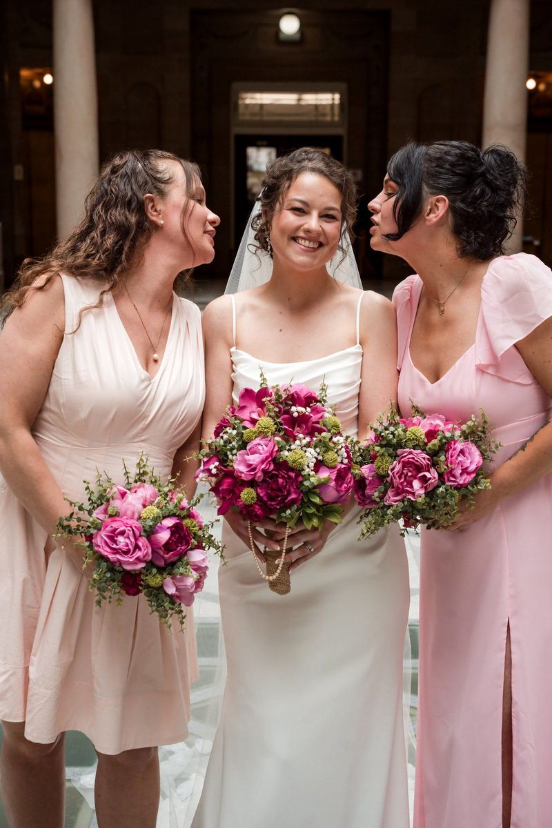 Christina shares a smile with two wedding party members holding pink bouquets