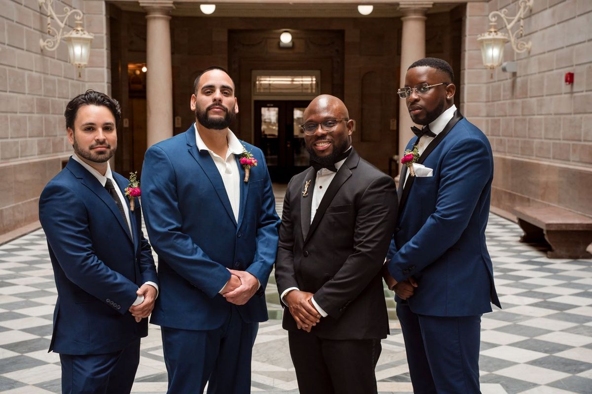 Tajay poses with three wedding party members in blue suits
