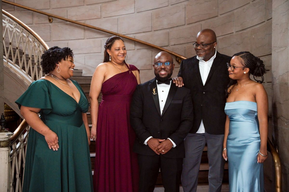 Tajay smiles with a small group of loved ones on the staircase