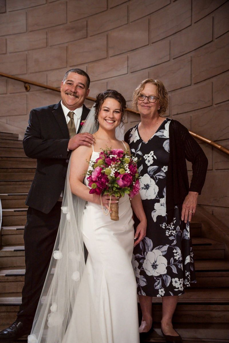 Christina poses between two loved ones with her pink bouquet