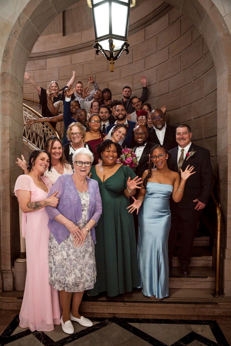 Christina, Tajay and their guests celebrate together in a large staircase group portrait