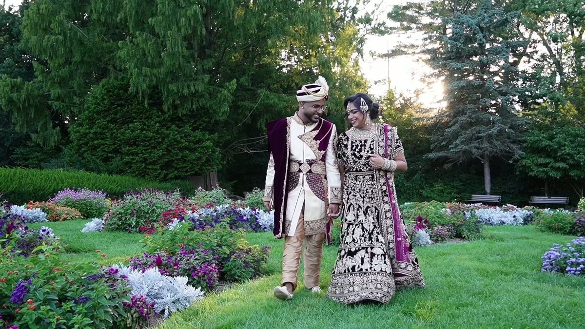 The couple walk together between the garden flower beds — video frame