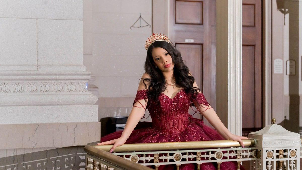A closer portrait of Genesis in her tiara at the brass stair railing