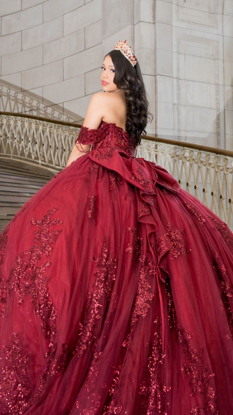 Genesis looks over her shoulder showing the bow and embroidery of her gown