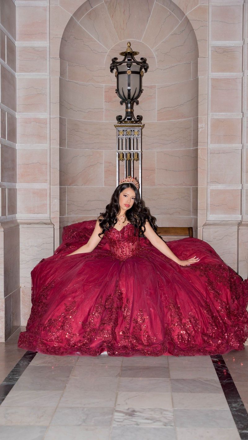 Genesis sits beneath an ornate lantern with her gown arranged around her