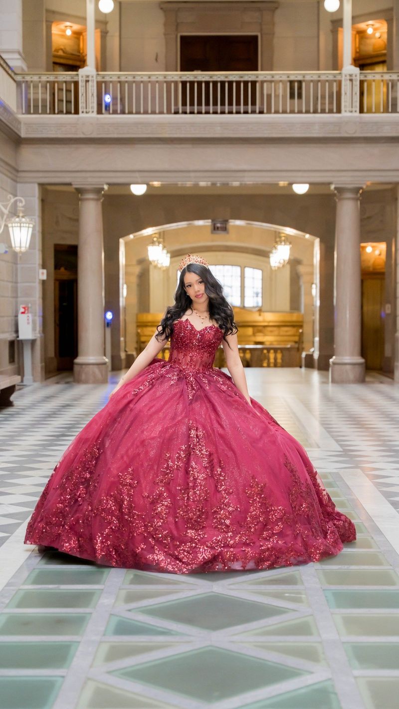 Genesis smiles toward the camera in her burgundy quinceañera gown on the patterned Hartford City Hall atrium floor