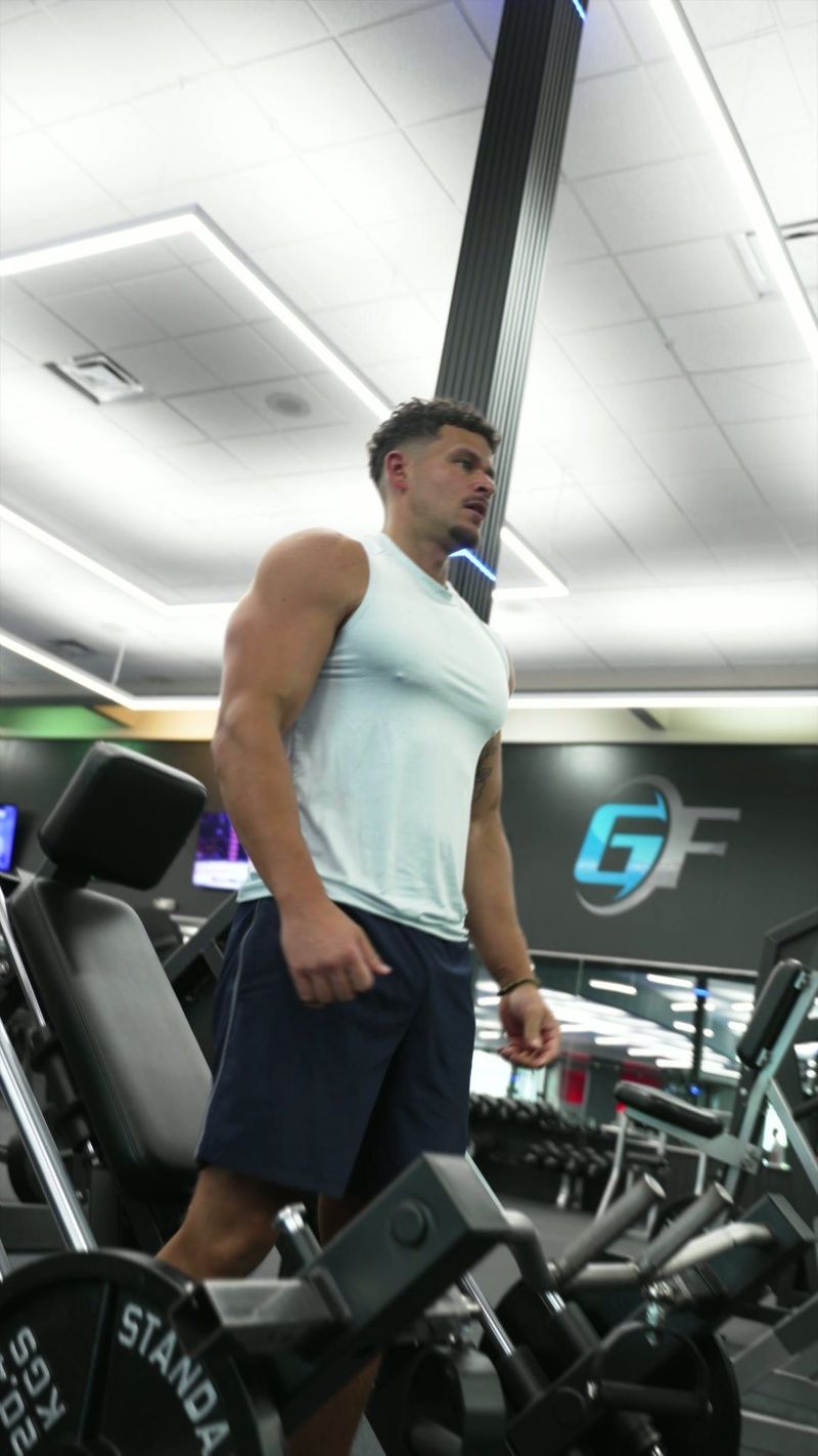 Athlete in a white sleeveless top among gym equipment at GF Fitness — video frame