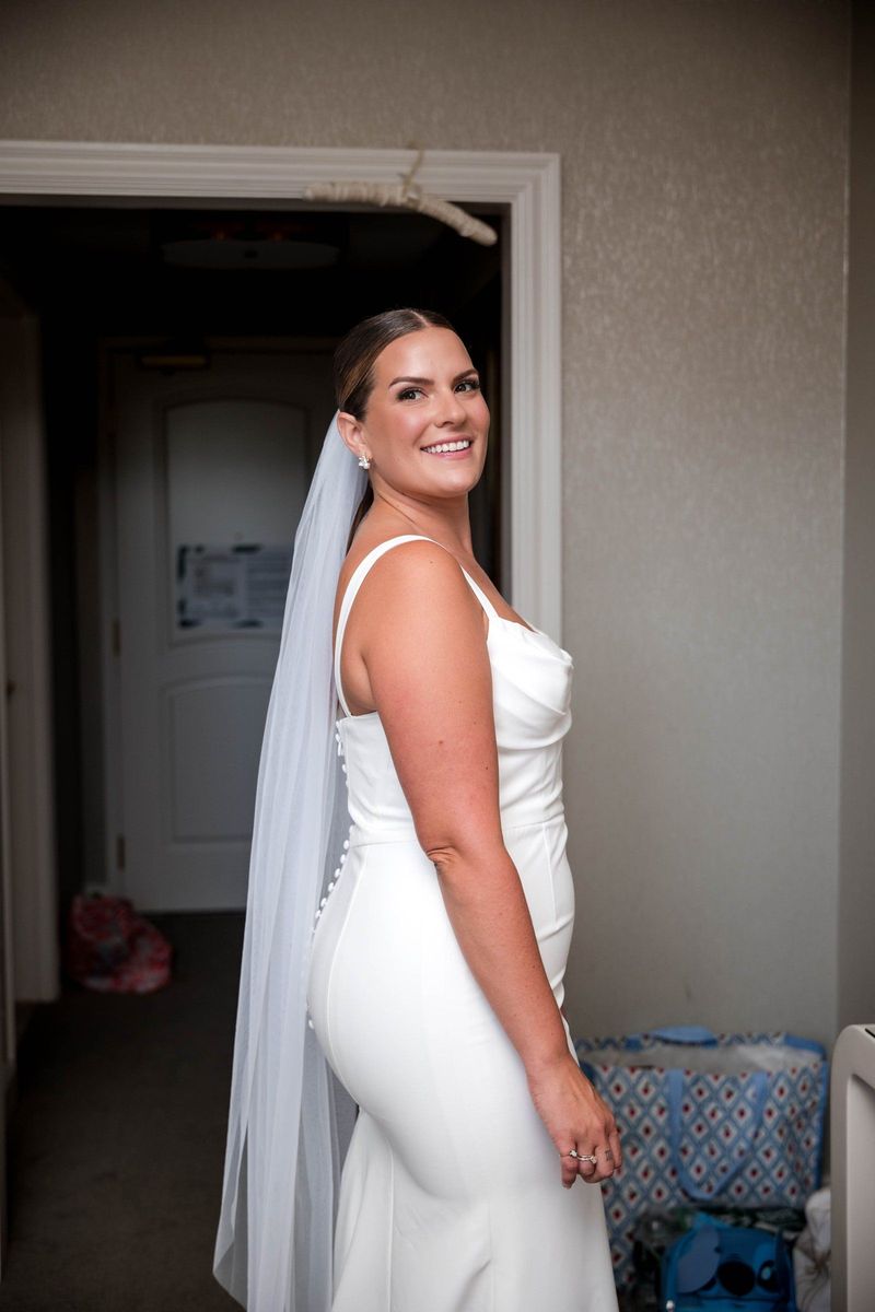 Thea smiles over her shoulder in her gown and veil