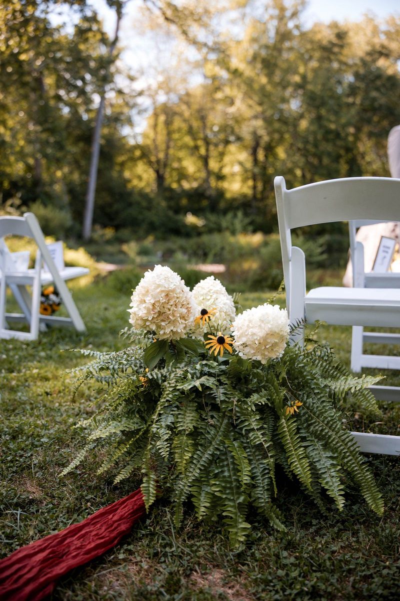 White flowers and greenery arranged beside a ceremony chair