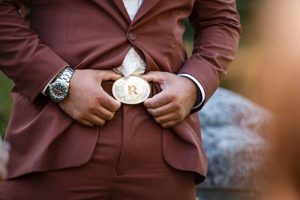 A close view of Jacob’s suit, watch and decorative belt buckle