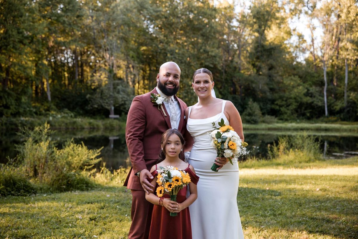 Jacob and Thea pose with a young wedding party member holding a bouquet