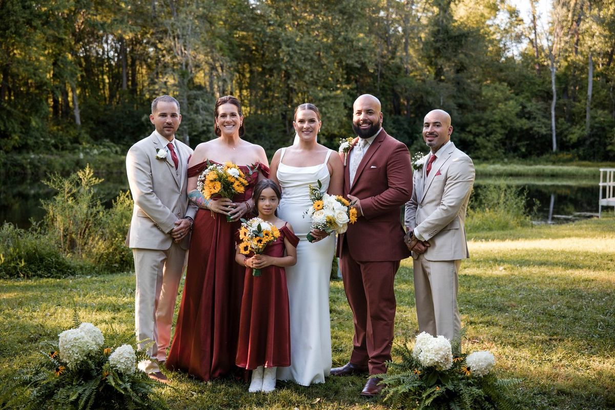 Jacob and Thea stand with their wedding party beside the pond