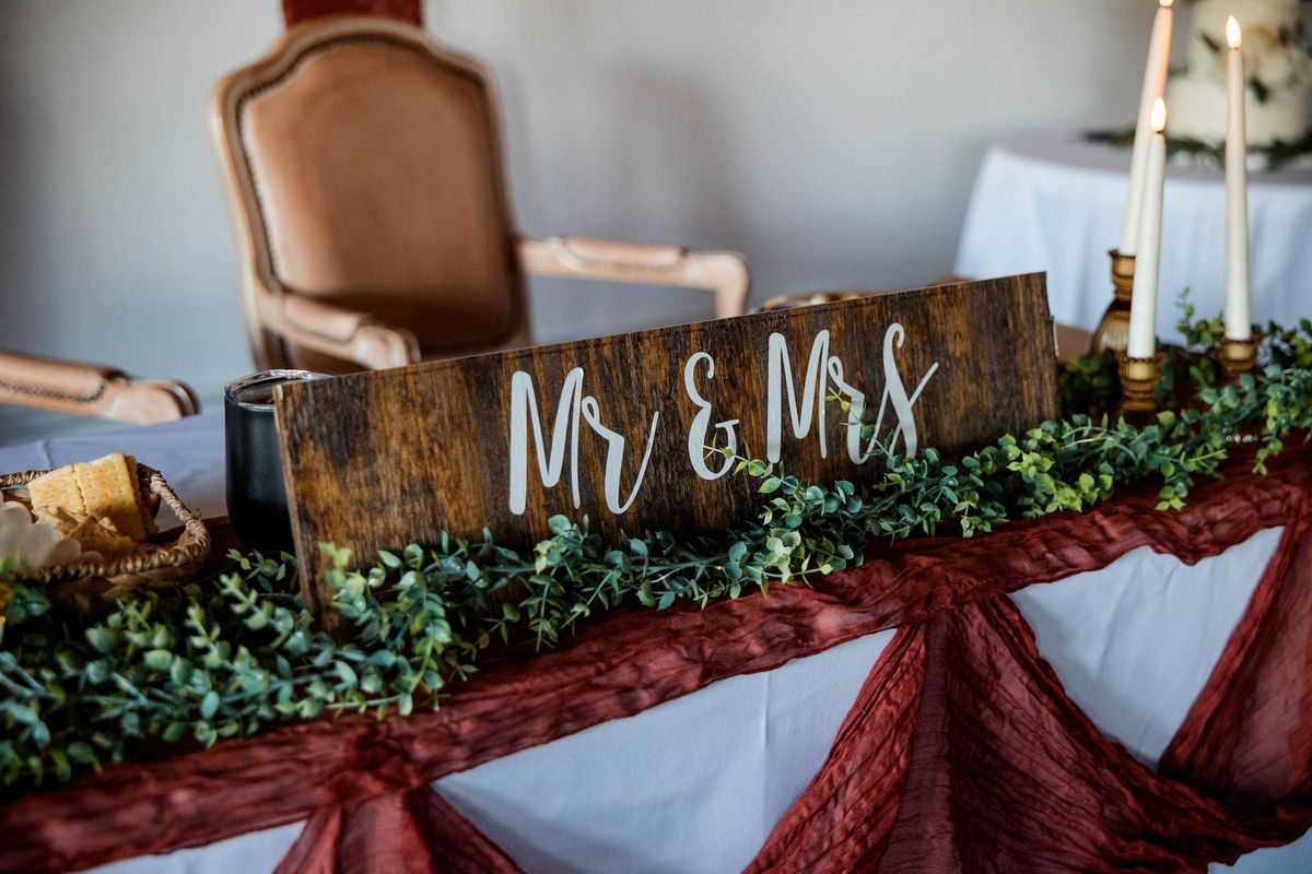 The sweetheart table with a wooden Mr and Mrs sign, candles and greenery