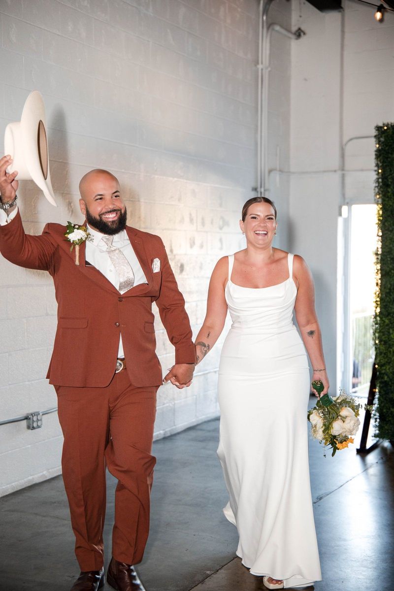 Jacob raises his white hat as he and Thea enter the reception