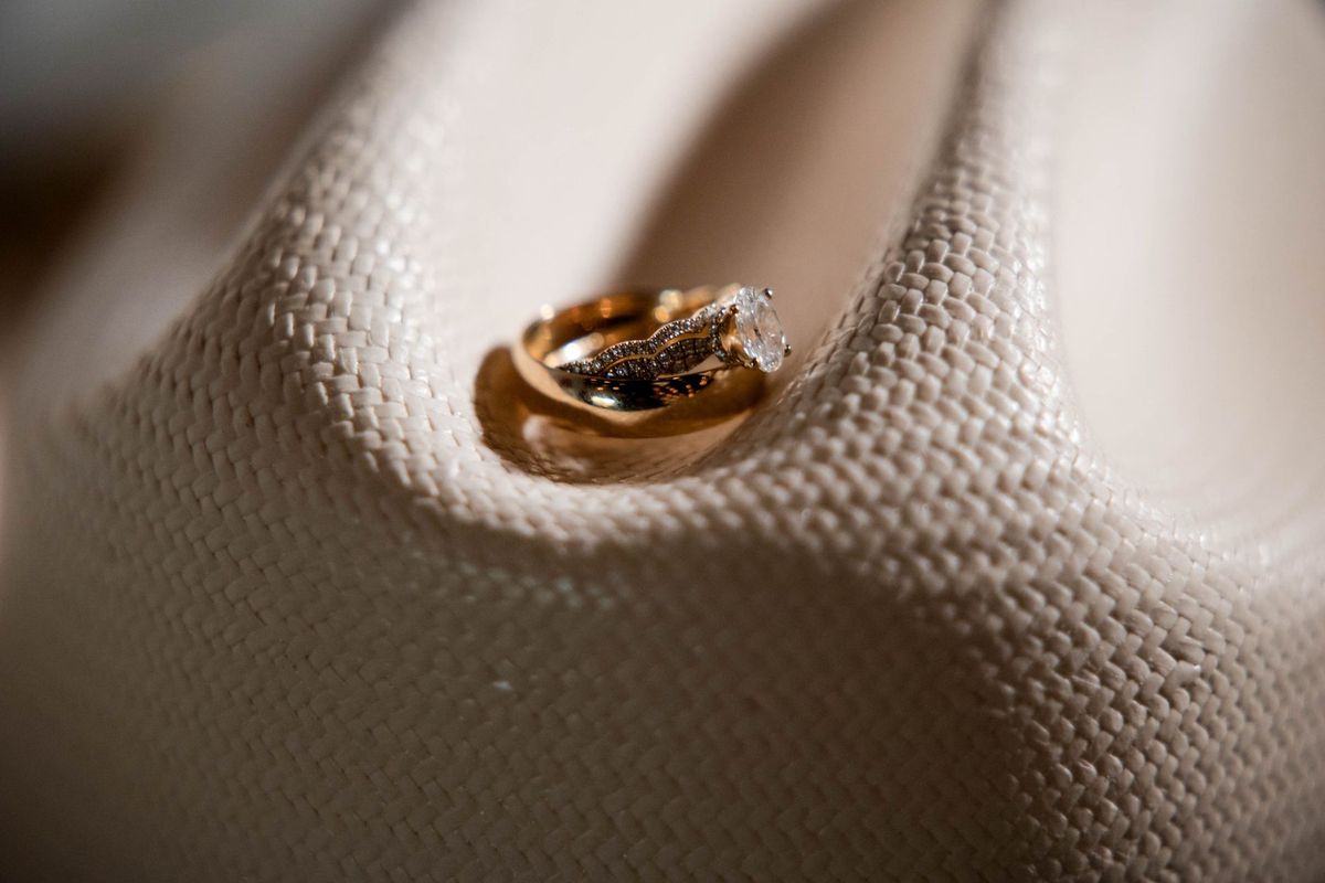 Wedding rings rest together on the brim of a white cowboy hat