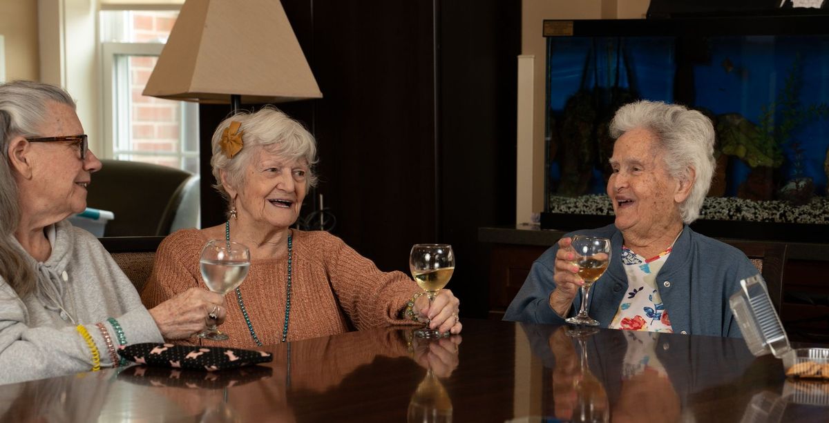 Smiling people at a table raising their glasses at Jerome Home