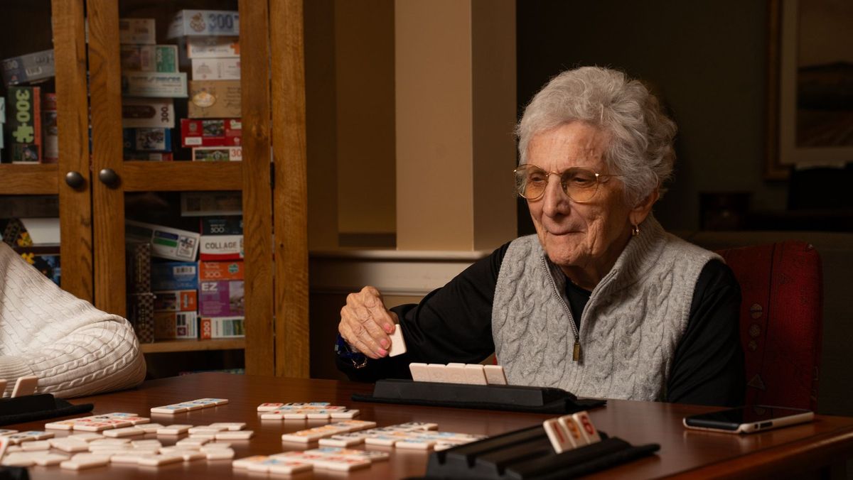 Smiling woman playing a tile game at a table at Jerome Home