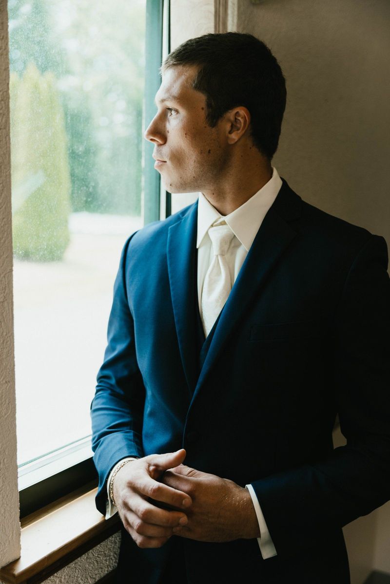 Max standing beside a window before the wedding
