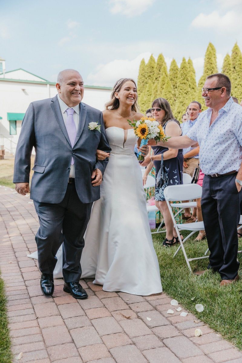 Mariana walking down the wedding aisle with a companion