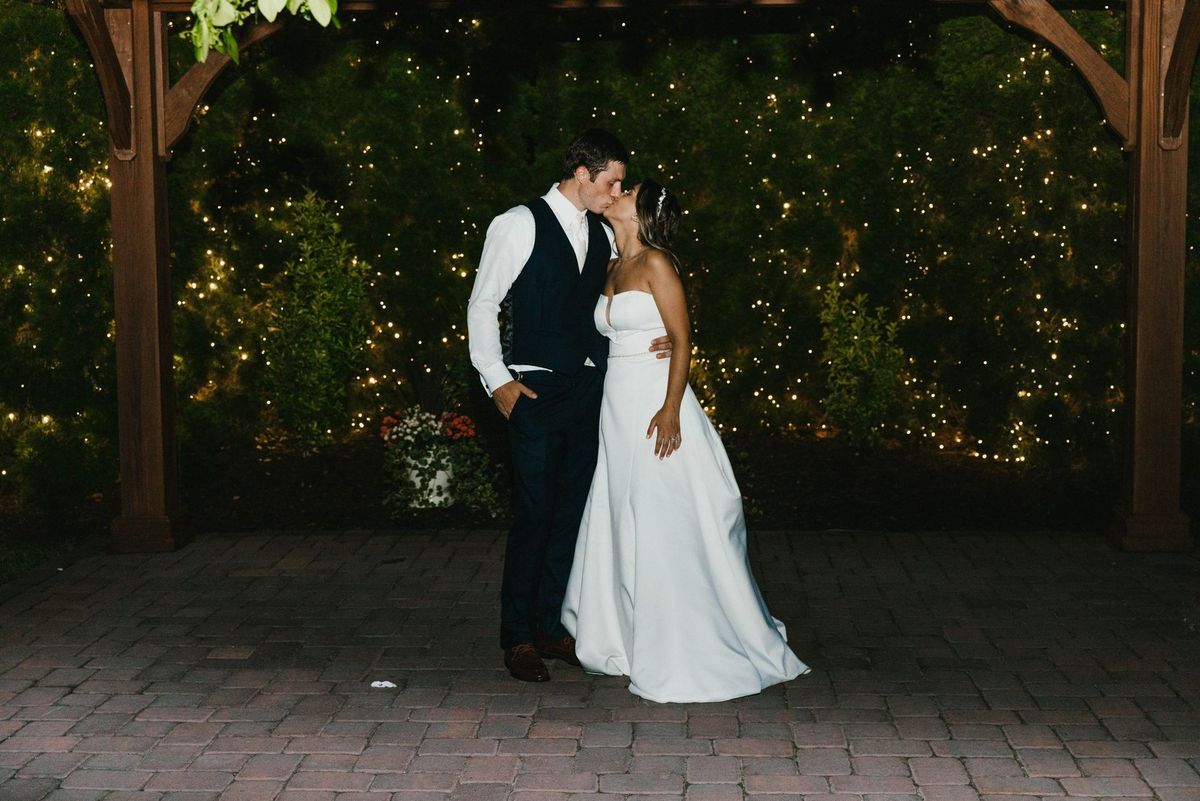 Mariana and Max kissing beneath an arbor at night