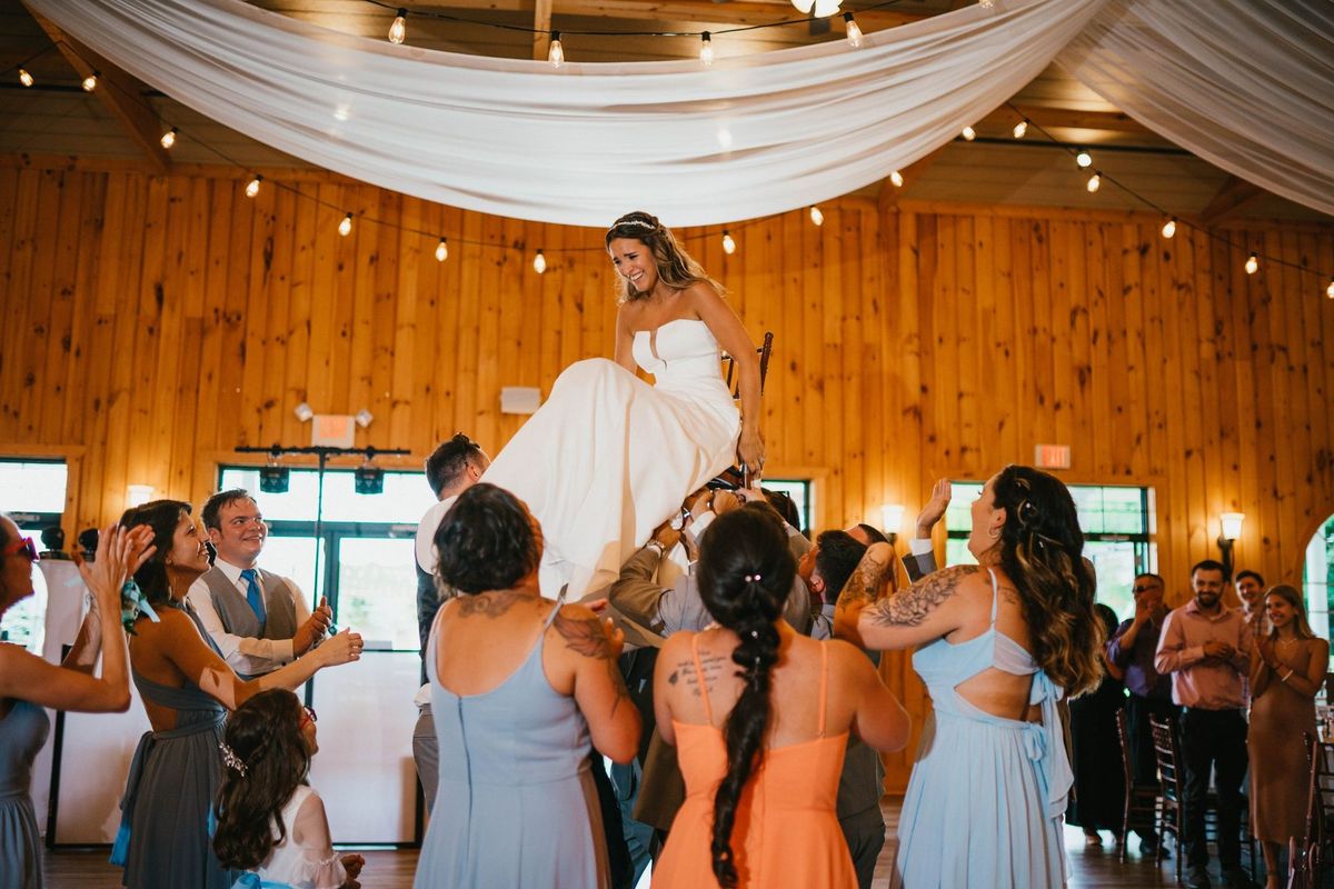 Mariana smiling while lifted above reception guests