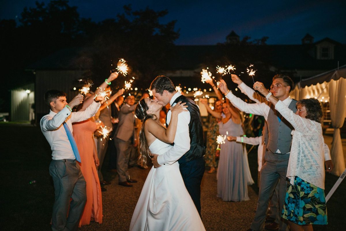 Mariana and Max kissing surrounded by guests holding sparklers