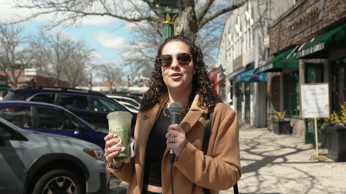 Robyn presents with a microphone on a West Hartford shopping street