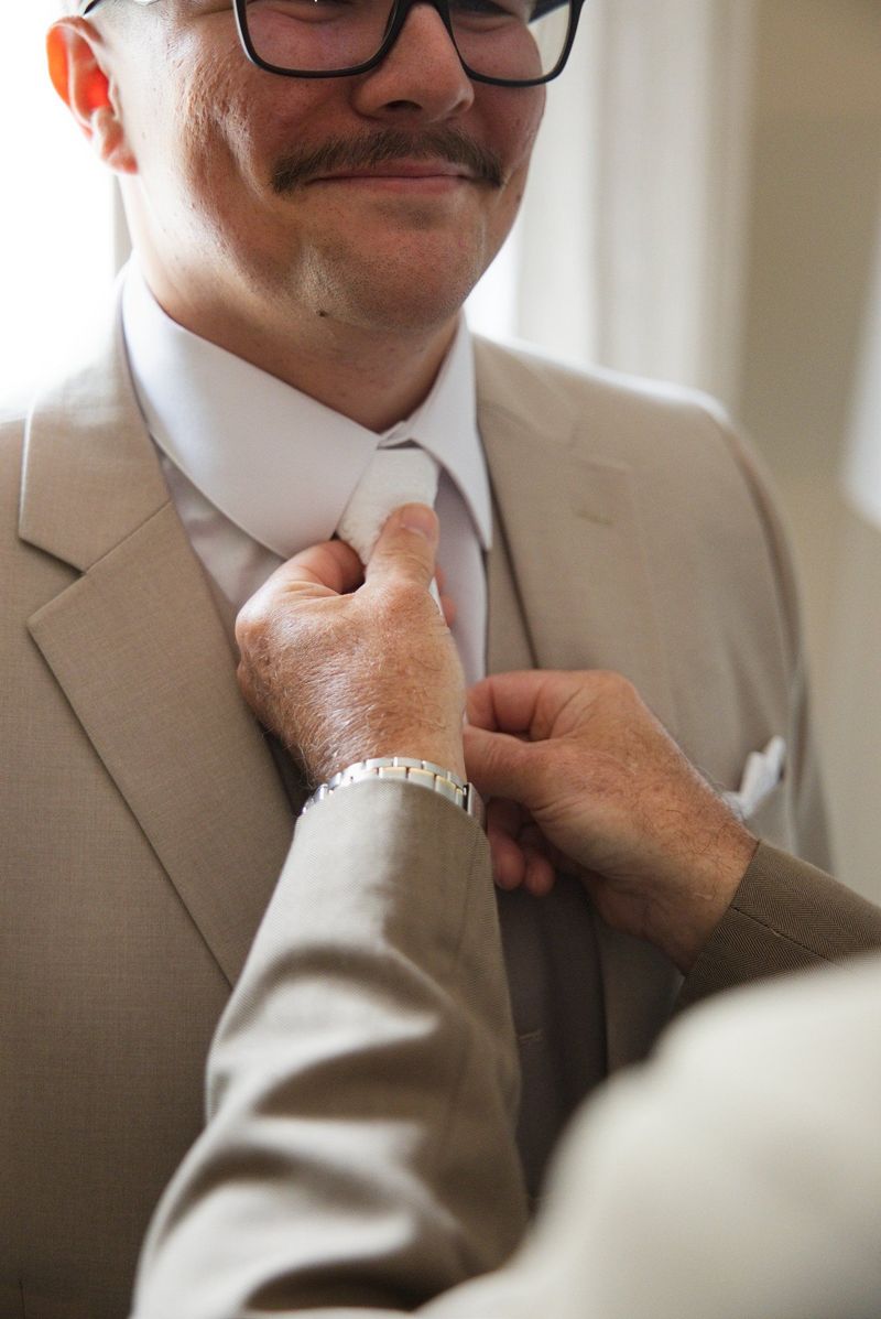 A close view of helping hands straightening Mat’s tie