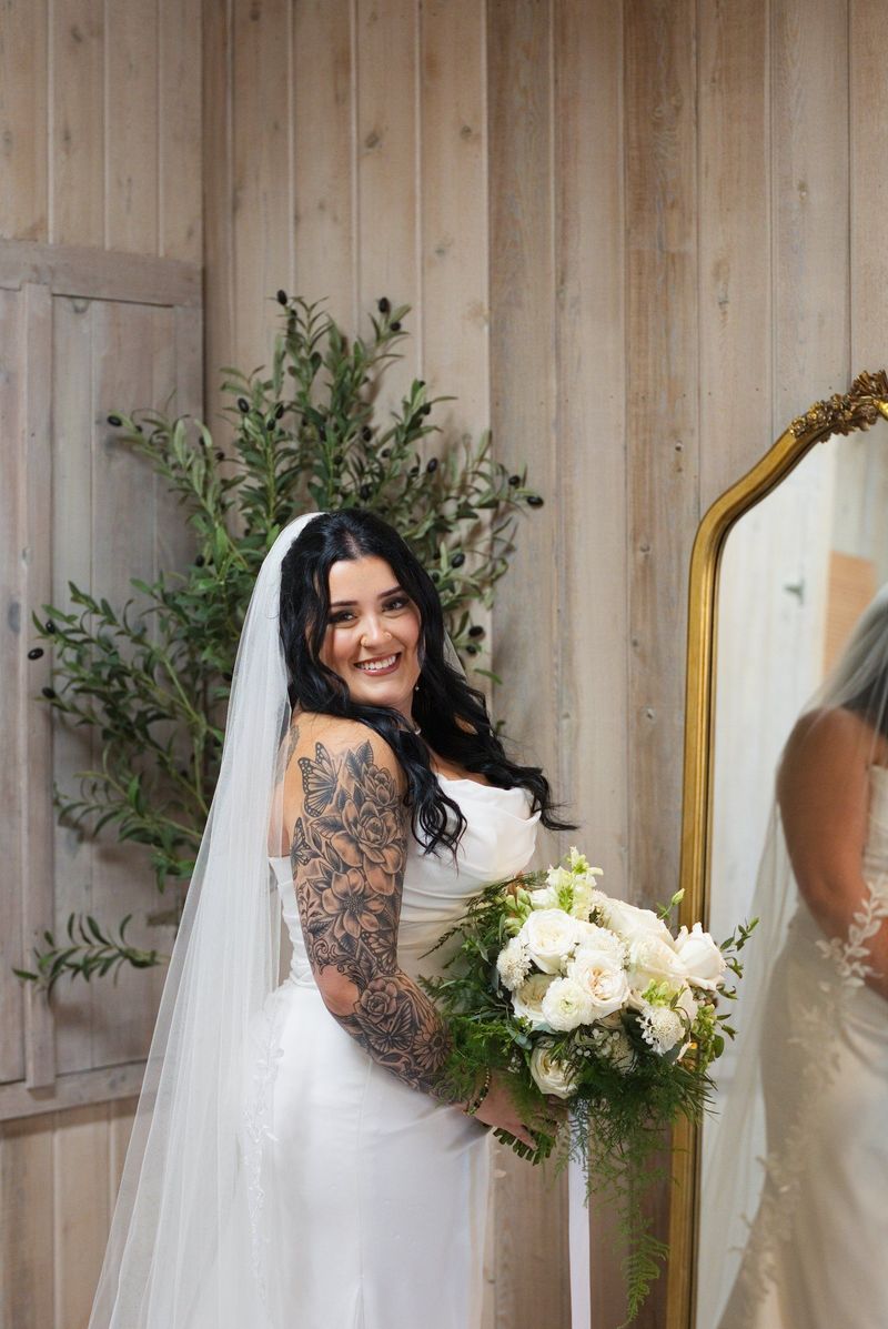 Sadie holds her bouquet beside a mirror in the wedding suite
