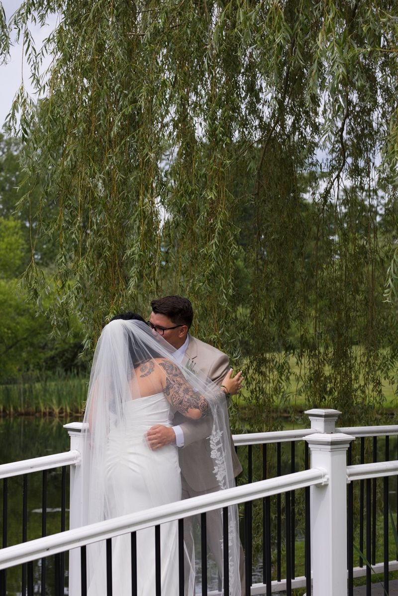 Sadie and Mat embrace beneath the willows beside the bridge