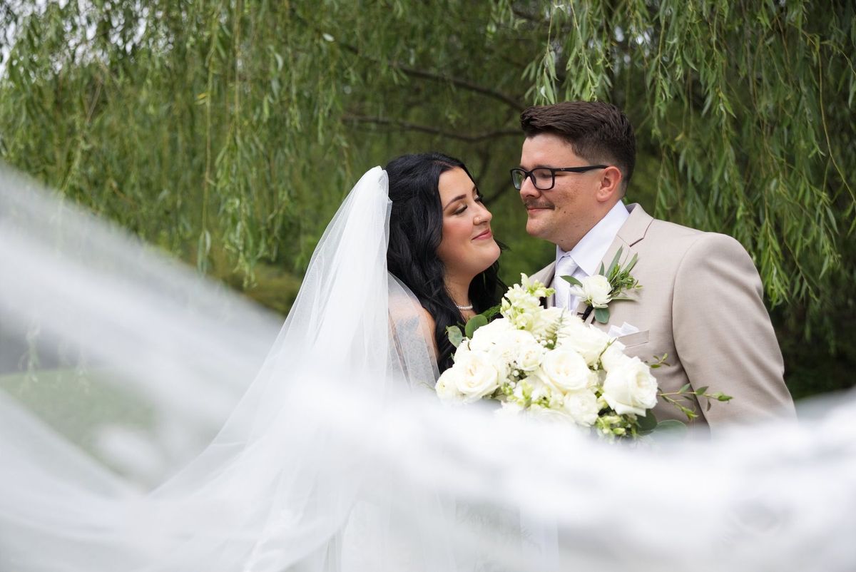 A close portrait of Sadie and Mat framed by her veil