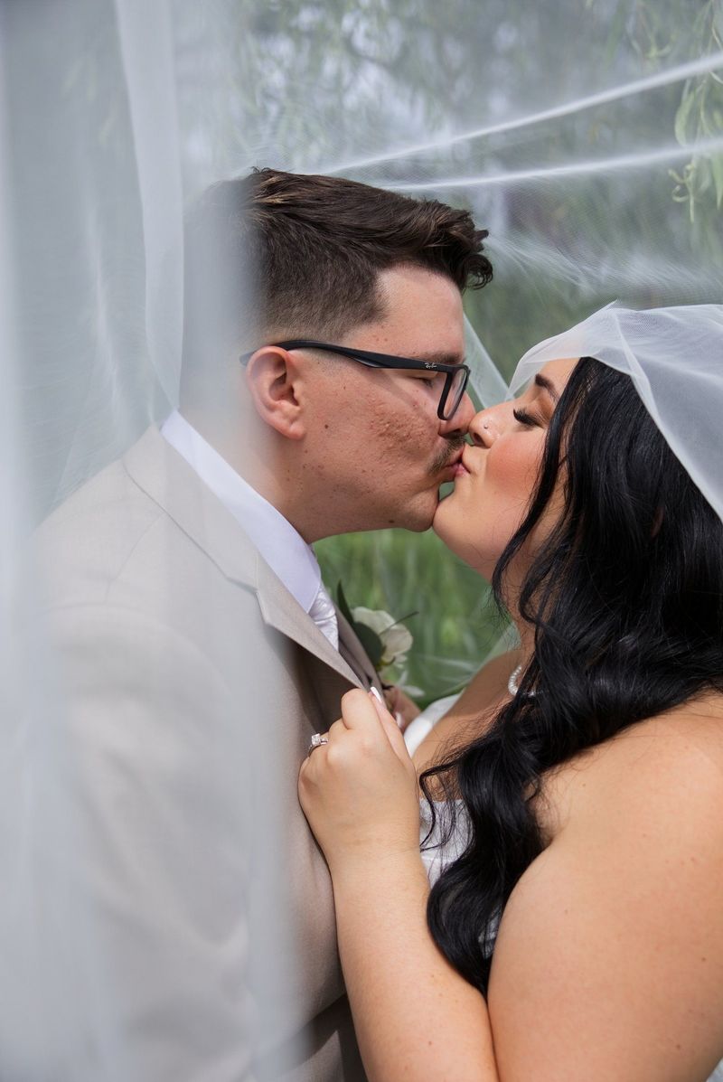 Sadie and Mat kiss beneath a translucent veil