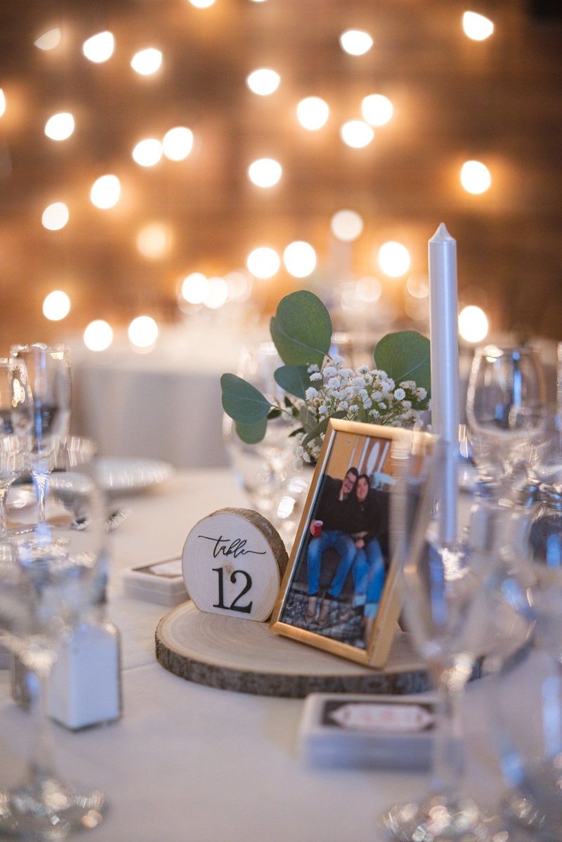 A reception table with a framed photograph, flowers and glowing lights