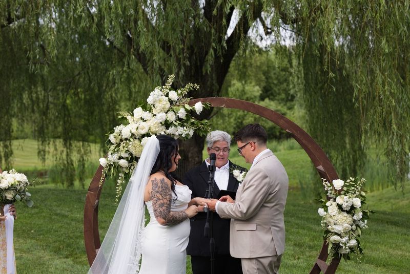 Sadie and Mat exchange rings beneath the circular floral arch