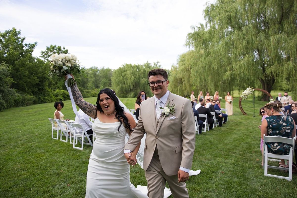 Sadie lifts her bouquet beside Mat after their ceremony
