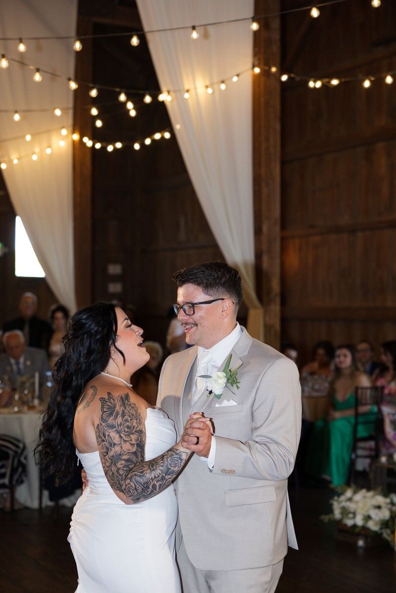 Sadie and Mat smile during their first dance beneath string lights