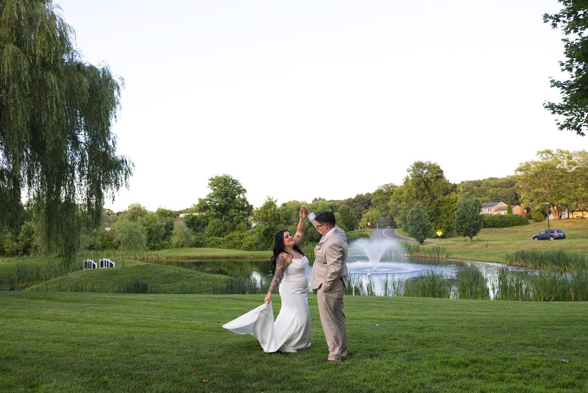 Mat turns Sadie beneath his raised hand beside the pond