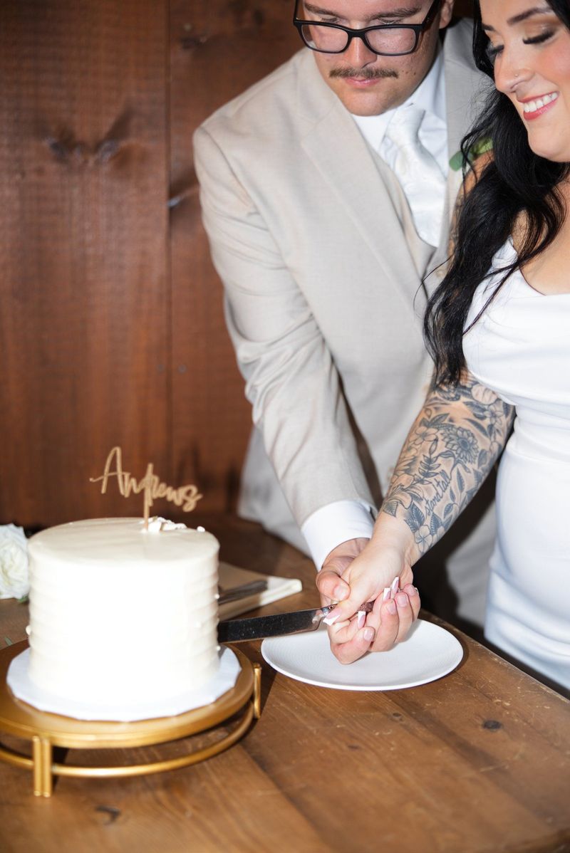 Sadie and Mat’s hands guide the knife as they cut their wedding cake